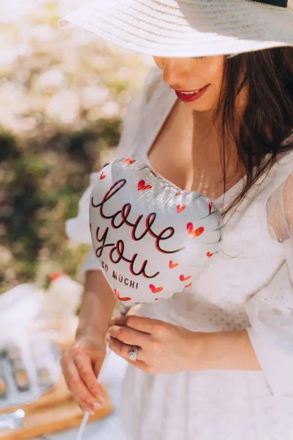 young woman holding I Love You balloon